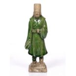 A Chinese standing scholar Tang dynasty with green glaze and on a stepped square base 21cm high