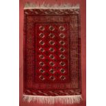 A TEKKE WINE GROUND RUG decorated with three rows of medallions within a multiple border, 181cm x