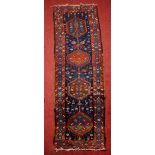 A PERSIAN KARAJA RUNNER with four central interlocking medallions on a dark blue ground within a