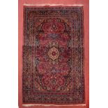 A PERSIAN MESHED FLORAL PATTERNED RUG with central multiple medallion and blue ground border,