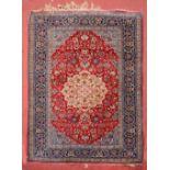 A PERSIAN ISFAHAN RUG, the central foliate medallion within a red ground field and blue border,