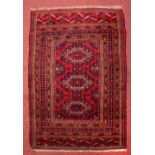 A PERSIAN YOMUD RED GROUND MAT with three interlocking medallions within a multiple border, 121cm