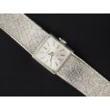 A LADY'S 9CT WHITE GOLD BRACELET WATCH BY TISSOT, the square silvered dial with baton markers, to