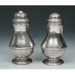 TWO 18TH CENTURY BALUSTER SHAPED PEPPER POTS, both standing on turned stepped feet and with