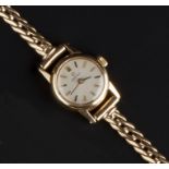 A LADY'S 9CT GOLD WRISTWATCH BY OMEGA, the circular signed silvered dial with baton markers, to a