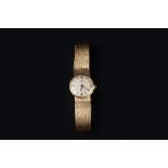 A LADY'S 9CT GOLD BRACELET WATCH BY OMEGA, the circular signed silvered dial with Arabic numerals