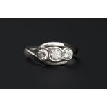 A DIAMOND THREE STONE RING, of crossover design, the graduated round brilliant-cut diamonds in