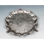 A LATE GEORGE II SILVER CARD TRAY with shell and scroll border and standing on three cabriole