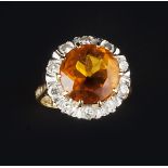 A CITRINE AND DIAMOND CLUSTER RING, the circular mixed-cut citrine claw set within a border of round