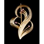 A RUBY SET BROOCH, designed as a scrolled ribbon of pierced and textured design, highlighted with