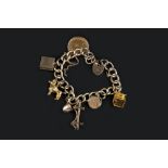 A CHARM BRACELET, the 9ct gold curb-link bracelet with padlock clasp, suspending a collection of