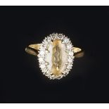 A YELLOW TOPAZ AND DIAMOND CLUSTER RING, the oval mixed-cut yellow topaz claw set within a border of