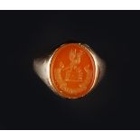 A HARDSTONE SIGNET RING, the oval cornelian panel with incised crest and motto, to mount stamped '