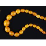 AN AMBER BEAD NECKLACE, comprising a single strand of graduated amber beads, measuring approximately