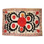 AN UZBEK TRIBAL SUZANI with a central scrolling red and black stylized floral design on a white