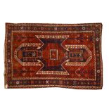 AN ANTIQUE KASAK RED GROUND RUG with an all over polychrome hooked motif within a blue ground star