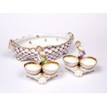 A PAIR OF BERLIN PORCELAIN FIGURAL TABLE SALTS each modelled with a cherub with twin oval baskets,