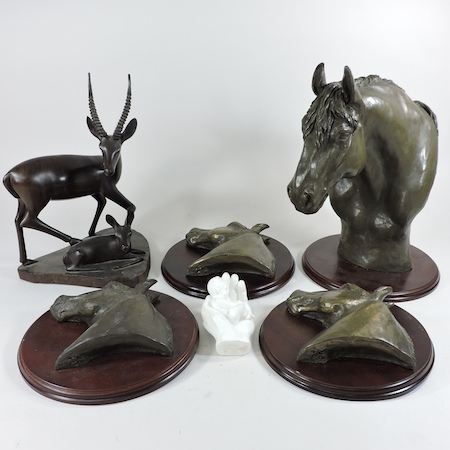 A set of three bronzed plaques, each decorated in relief with a horse's head,