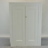 A white painted pine cabinet, fitted with shelves and enclosed by a pair of panelled doors,