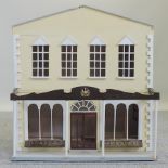 A cream painted doll's house, in the form of a draper and haberdashery shop,