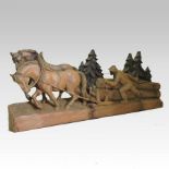 A black forest softwood carving of two horses and a woodman dragging logs, on a plinth base,