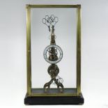 A brass skeleton clock, having an enamelled chapter ring, contained in a glazed case,