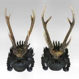 A pair of Chinese carved rosewood and antler mounted wall masks,