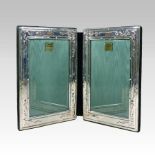A modern silver double photograph frame, of hinged rectangular form, with scrolled decoration,