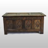 An 18th century carved oak coffer, with panelled lid and carved front,