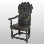 A 19th century carved oak wainscot armchair, the arched back decorated with a central flower,