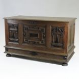 An 18th century oak coffer, with a hinged lid, over geometric moulded panels, on bun feet,