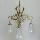 An Arts and Crafts brass three branch ceiling light, with cut glass shades,