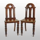 A pair of Victorian walnut hall chairs, the arched back carved with quatrefoil decoration,