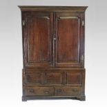 An 18th century oak press cupboard, enclosed by a pair of fielded panelled doors,
