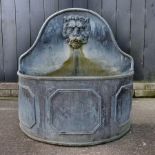 A lead garden fountain, of curved shape, decorated in relief with a lions mask spout,
