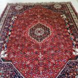 A Heriz woollen carpet, with a central hooked medallion and horse head design, on a red ground,