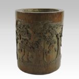 A Chinese carved bamboo brush pot, decorated with figures amongst trees,
