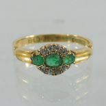 An 18 carat gold emerald and diamond three stone ring,