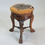 A 19th century carved walnut revolving piano stool, having a buttoned leather padded seat,