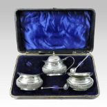 An early 20th century silver condiment set, comprising a mustard with a blue glass liner,
