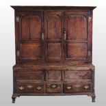 An 18th century oak Welsh hanging cupboard, the upper section with panelled doors and sides,