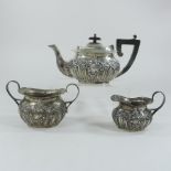 An early 20th century three piece silver tea service, of oval shape, with repousse decoration,