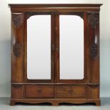 A Victorian carved walnut double wardrobe, enclosed by a pair of mirrored doors,