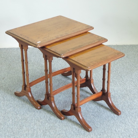 A nest of three walnut and cross banded occasional tables,