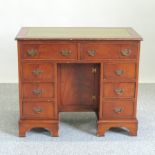 A George III style knee-hole writing desk, with a green leather inset top,