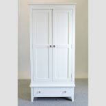 A white painted double wardrobe, with a single drawer,