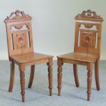 A pair of Victorian carved walnut hall chairs, with solid seats,