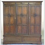 A 1920's Jacobean style oak triple wardrobe, with a fitted interior and drawers below,