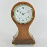 An Edwardian walnut cased balloon shaped mantel clock, on brass ball feet,