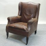 An early 20th century brown upholstered wing back armchair,